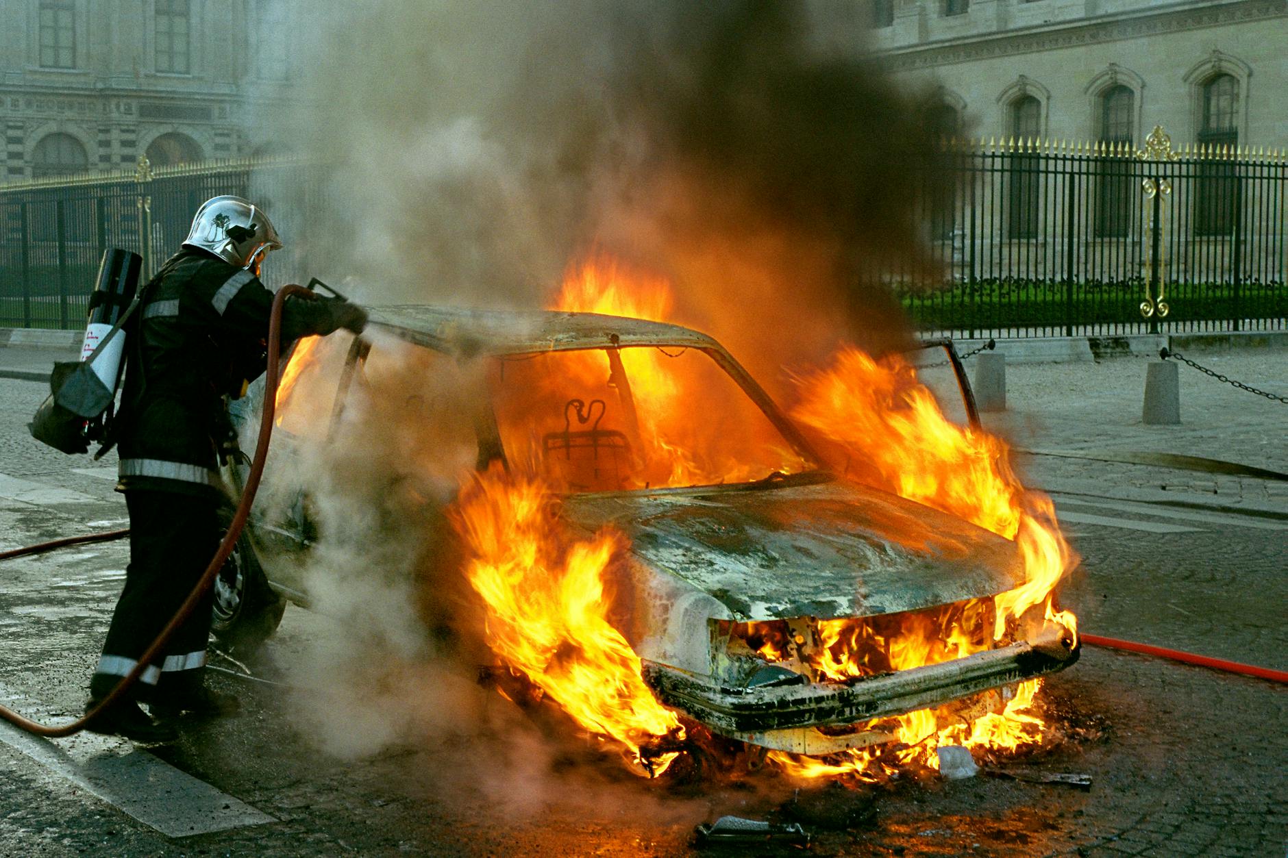 a fireman extinguishing a car on fire